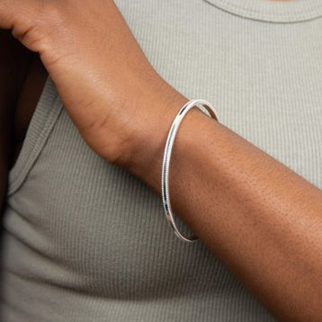 Mill grain edge bangle in silver.